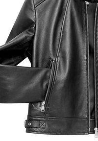 Giubbotto di pelle nera con una texture liscia, cerniere argentate sulle tasche e un dettaglio a scatto in fondo. Vestibilità sartoriale con un design moderno.