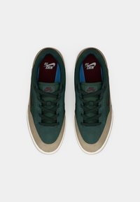 Nike sneakers with a green suede upper, beige accents, dark green laces, and red and blue inner lining. Flat rubber sole.
