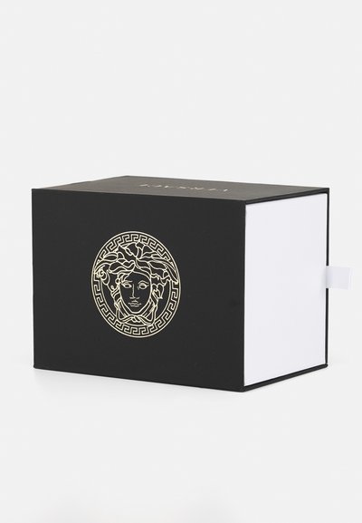 Črna škatla z belo notranjostjo, na sprednji strani z zlatim dizajnom Meduze, obkrožena z grškim ključnim vzorcem. Vključuje bel podaljšek.