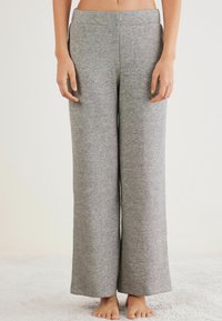 Pantalones de salón amplios y grises hechos de una tela suave y texturizada. Cuentan con una cinturilla suave y un corte relajado desde la cintura hasta el dobladillo.