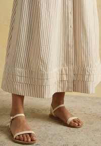 Prúžkované bavlnené midi šaty s skladaným lemom, doplnené béžovými sandálmi na remienky s nastaviteľným okolo členku a plochou podrážkou.