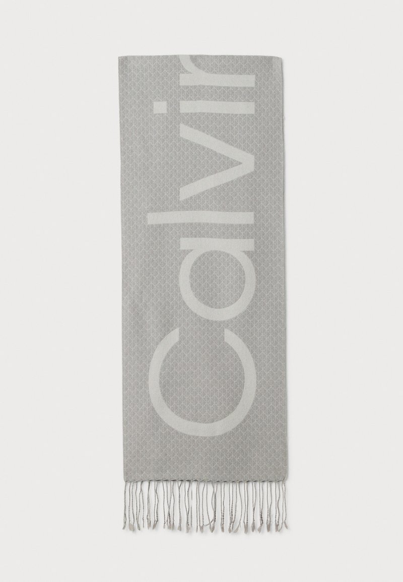 fular gri deschis cu un model geometric subtil și litere mari, de culoare deschisă, care scriu "Calvin" vertical, terminându-se în franjuri.