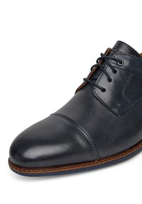 Tmavě modré kožené společenské boty s hladkým povrchem, zaoblenou špičkou a šněrovacím designem. Obsahují prošívání a hnědou podrážku.