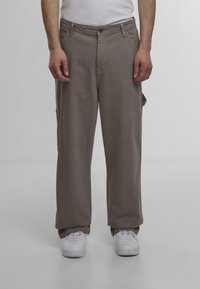 Lysebrune cargo bukser med en afslappet pasform, der har sidelommer, knaplukning og bæltestropper. Sammen med hvide sneakers.