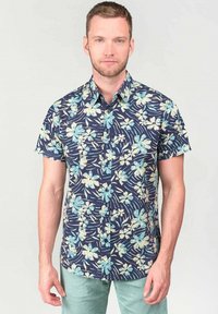 Camisa de manga corta en navy con un estampado floral de flores en azul claro y crema. Cuello de botón y corte relajado.