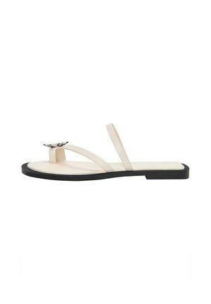 Sandalo piatto color crema con sottili cinturini e una farfalla decorativa argentata sull’anello dell’alluce, suola nera, vista laterale su sfondo bianco.