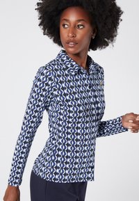 Long-sleeved shirt in navy blue with a geometric white pattern. Features a collar, button placket, and slim fit design. Soft texture.