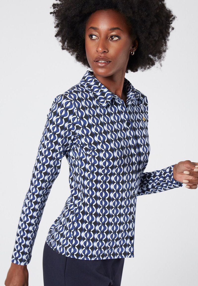 Lange mouwen shirt in marineblauw met een geometrisch wit patroon. Voorzien van een kraag, knopenlijst en slim fit ontwerp. Zachte textuur.