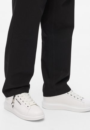 Witte sneakers met een gladde leren afwerking, ronde neus en platte zool. Voorzien van veters, merkbedrukking aan de zijkant en een zwarte accent.