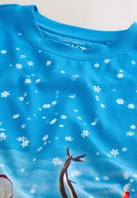 Modrá mikina s dlouhým rukávem s motivy sněhu, hladkou texturou a kulatým výstřihem. Viditelné vánoční designové prvky.