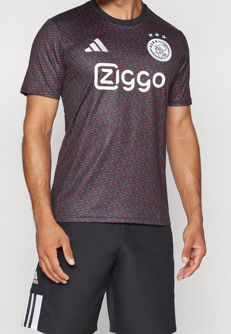 Černý a červený vzorovaný sportovní dres s kulatým výstřihem a krátkými rukávy, s bílým logem a textem na přední straně, vyrobený z lehkého materiálu.