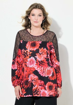 Sort bluse med stort rødt blomsterprint, lange mesh-blonderærmer, bådformet udskæring og tætsiddende nederkant. Tekstureret blonde kontrasterer med det glatte stof.