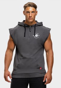 Grauer ärmelloser Hoodie mit Reißverschluss vorne, ausgestattet mit einer Fronttasche und einem Logo-Design auf der linken Seite. Weicher Stoff mit glatter Textur.