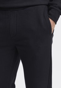 Navy sweatpants in soft cotton blend, featuring side pockets and a smooth texture. Tapered fit with a clean design and minimal stitching.