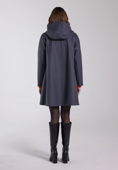 Mørkegrå vandtæt frakke med hætte, indsnævret talje og knælængde, parret med sorte knæhøje støvler. Glat tekstur og minimalistisk design.