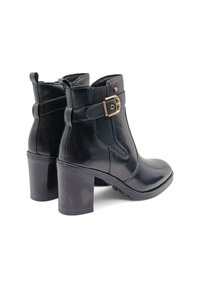 Stivali neri in pelle fino alla caviglia con una finitura liscia, caratterizzati da un dettaglio con chiusura in oro e un tacco spesso. I tacchi hanno suole in gomma per una maggiore aderenza.