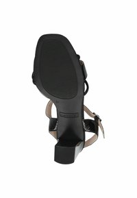 Sandale negre cu toc, având un design texturat al curelei, cu o finisare netedă și strălucitoare. Talpa este din cauciuc, cu nervuri pentru aderență. Mărimea este marcată cu 37.