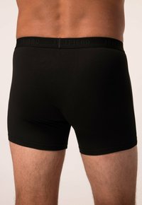 Černé boxerky z hladké tkaniny s elastickým pasem, na kterém je text "JP1880." Design je těsně přiléhající a minimalistický.
