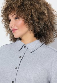 Lichtgrijze wolmix shirt met kraag, voorzien van donkergrijze knopen en een gestructureerde afwerking. Eenvoudig ontwerp met een getailleerde pasvorm.
