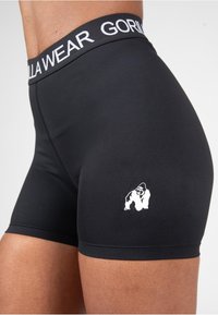 Melni sporta šorti ar baltu elastīgu jostasvīru, uz kura ir uzraksts "GORILLA WEAR". Priekšpusē, kreisajā augšstilbā, ir neliels balts gorillas logo.