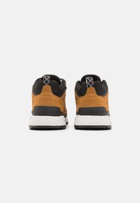 Brown suede and black fabric sneakers with white soles, featuring a padded collar and geometric-patterned pull tabs at the back.