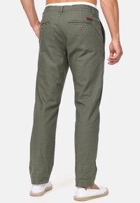 Oliwkowe, lekkie spodnie o luźnym kroju, z tylnymi kieszeniami zapinanymi na guziki oraz elastycznym pasem ze sznurkiem. Materiał teksturowany.