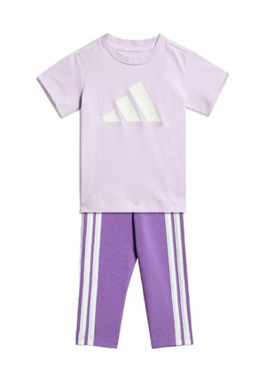 T-shirt en coton violet clair avec un logo triangulaire blanc ; leggings assortis violets avec trois bandes blanches le long des côtés.