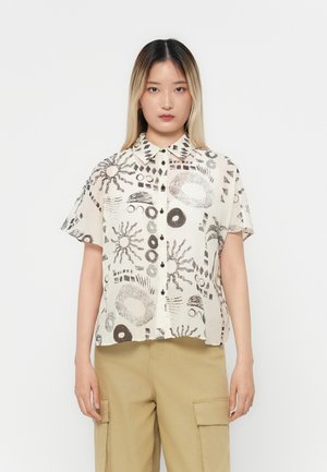Camicia a maniche corte in tessuto crema chiaro con motivi astratti neri, colletto a punta e chiusura con bottoni sul davanti.