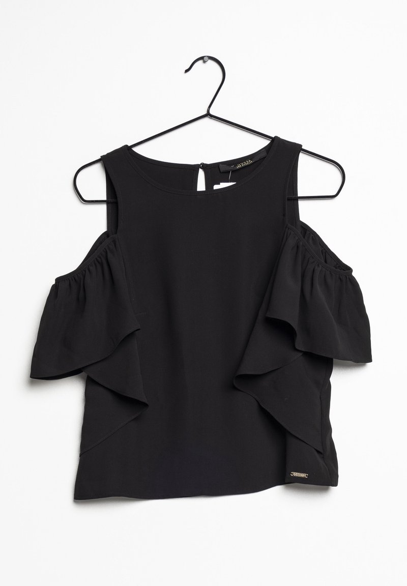 Blouse noire épaules dénudées avec manches à volants suspendue sur un cintre en fil noir sur fond blanc.