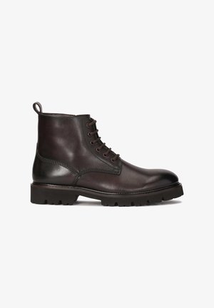 Bottes chevilles en cuir marron avec une finition texturée, bout rond et semelle en caoutchouc robuste. Comprend un système de laçage et une languette à l'arrière pour un enfilage facile.