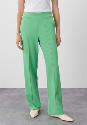 Green, wide-leg pants with textured fabric, featuring a high elastic waistband and subtle vertical seams, paired with cream-colored shoes.
