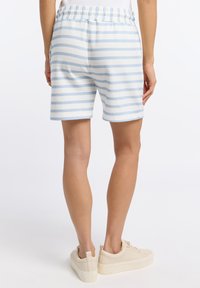 Blauw en witte gestreepte shorts van zacht materiaal, met een elastische tailleband en een ontspannen pasvorm. Gepaard met lichtgekleurde sneakers.