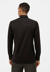 Zwarte lange mouwen shirt met een klassieke kraag, gladde textuur en knopensmanchetten; heeft subtiele stikdetails langs de rug.