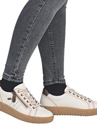 Sneaker casual bianche con accenti beige, dettagli con lacci e cerniera laterale. Presentano una suola beige testurizzata e un piccolo design perforato sul lato.
