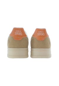 Sneakers in suede tan con talloni arancioni che presentano la dicitura "SINCE 1890" in bianco, suola in gomma e un design semplice e minimalista.