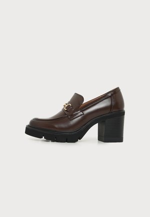 Mocassin en cuir marron foncé avec talon bloc noir épais et boucle décorative dorée sur le côté, sur fond clair uni.