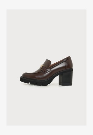 Mocassin en cuir marron foncé avec talon bloc noir épais et boucle décorative dorée sur le côté, sur fond clair uni.