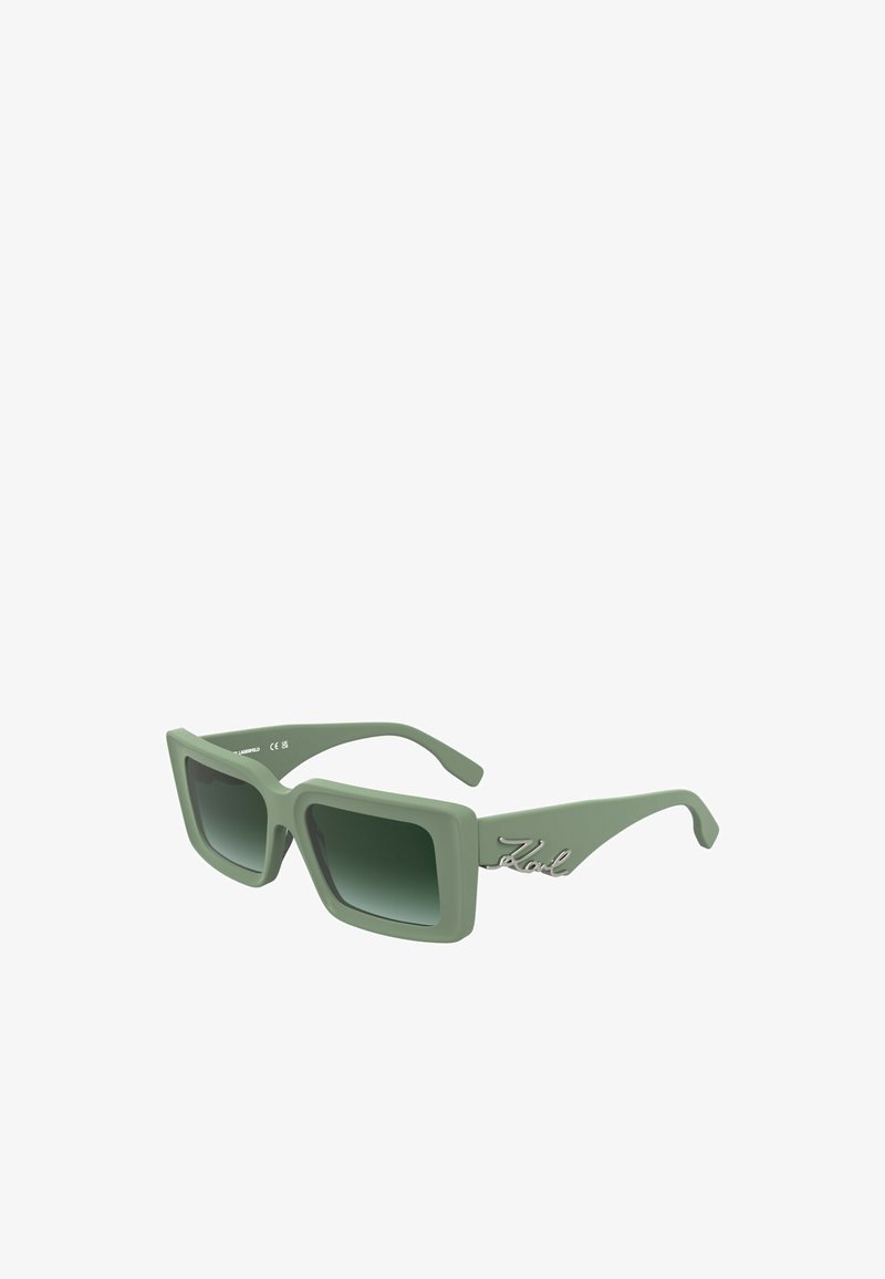 Occhiali da sole verde quadri con lenti sfumate. Presentano una finitura opaca e un logo argentato sul templete. Design robusto e oversized.
