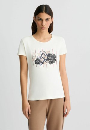 T-shirt bianco in cotone con maniche corte, collo rotondo e stampa grafica floreale in nero e rosa, caratterizzata da strisce verticali rosse.