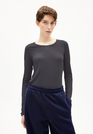 Langsleeve, ronde hals top van donkergrijze stof, gecombineerd met navy blauwe joggingbroek met een elastische tailleband en zijzakken.