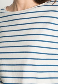 Randig t-shirt med horisontella blå och vita ränder, gjord av mjuk bomullstyg med vid halsringning och avslappnad passform.