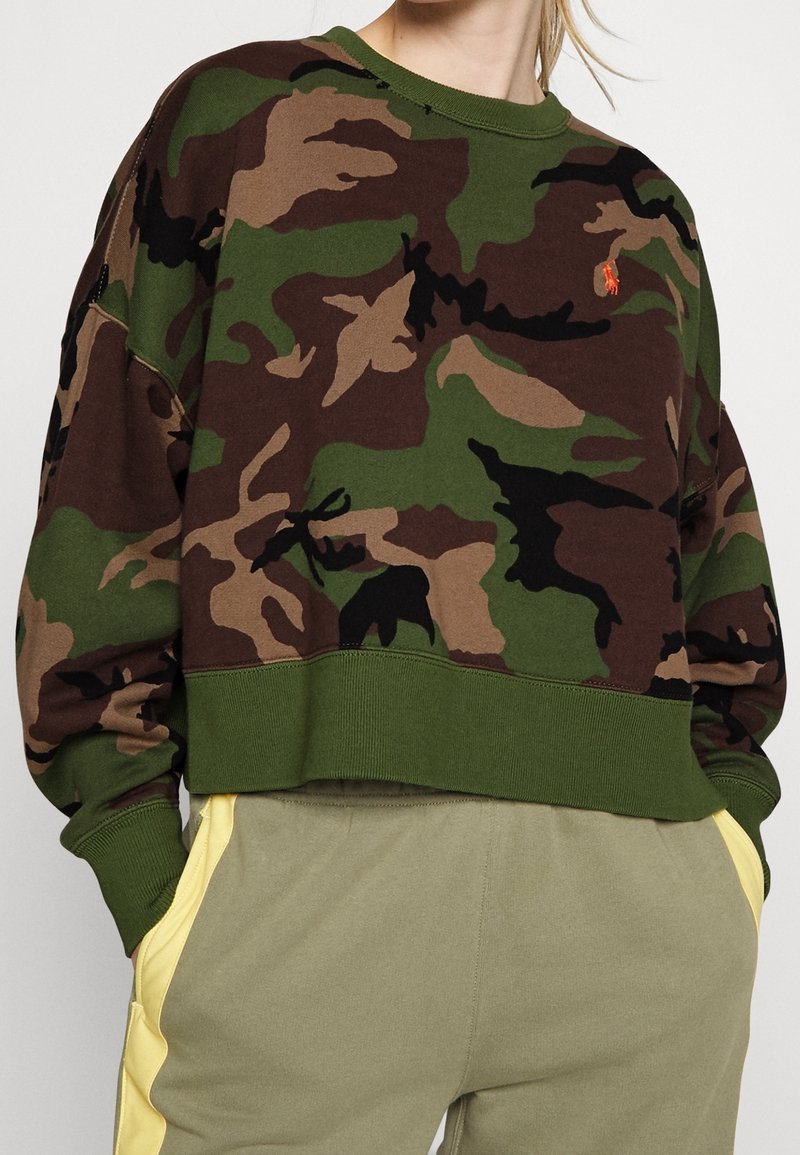 Camo sweatshirt featuring earth tones like green, brown, and black, with a ribbed neckline and hem, cropped design, and small logo detail.