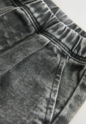 Material de denim negru elastic cu un finisaj texturat, prezentând o talie pliată și cusături proeminente de-a lungul buzunarelor și cusăturilor.