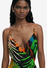 Vestido multicolorido con patrones de hojas tropicales, diseño de escote en V y tirantes ajustables decorados con cuentas de madera. Tejido suave y ligero.