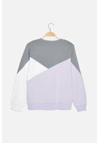 Sweat-shirt avec blocs de couleur géométriques en gris, blanc et lavande, suspendu à un cintre en bois sur un fond blanc.