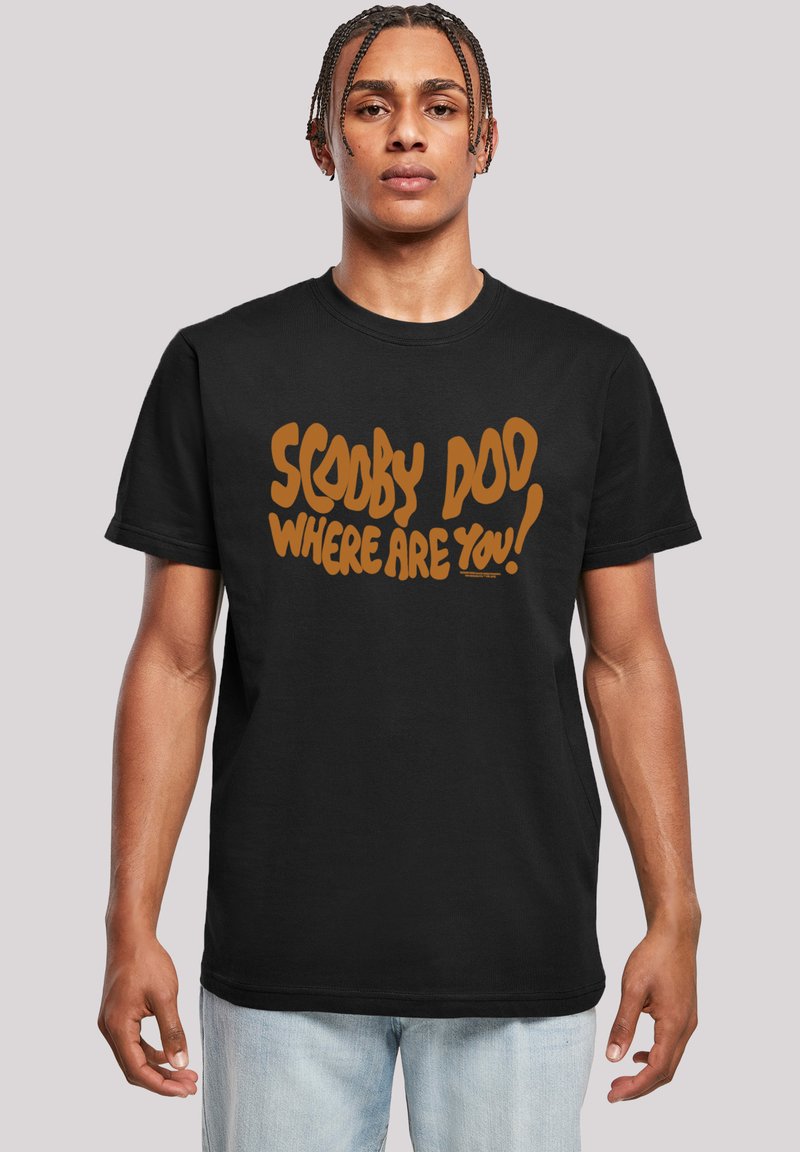 Černé bavlněné tričko s rezavě hnědým textem: „SCOOBY DOO, KDE JSI!“ Design má tučný, hravý font. Pohodlný střih s krátkým rukávem.