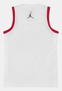 Biała siatkowa koszulka do koszykówki z czerwonym wykończeniem. Na plecach czarny logo Jumpman i napis "NIKE". Bez rękawów, lekka tekstura.