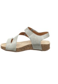 Silberne Leder-Sandalen mit offener Zehenpartie und gekreuzten Riemen. Korksohle sorgt für Textur. Minimalistisches Design mit flachem Profil.