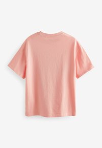 Camiseta de algodón rosa con mangas cortas y escote redondo. Textura suave y corte relajado. Sin patrones o acentos visibles.