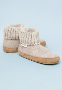 Beige felt slippers with a knitted cuff and brown suede soles, featuring a rounded toe and visible stitching details.